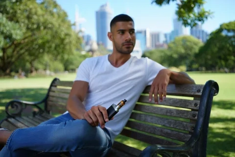 A person using their recharge vape in an Australian outdoor setting, like a park.